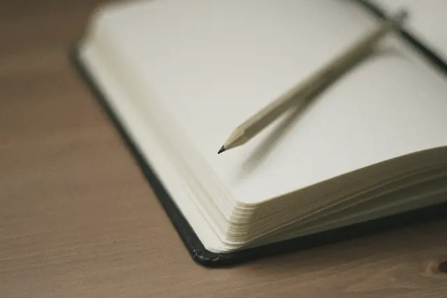 Masada açık duran boş bir defter ve kalem